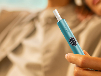 شخص يحمل علبة IQOS غير مفتوحة بعد.